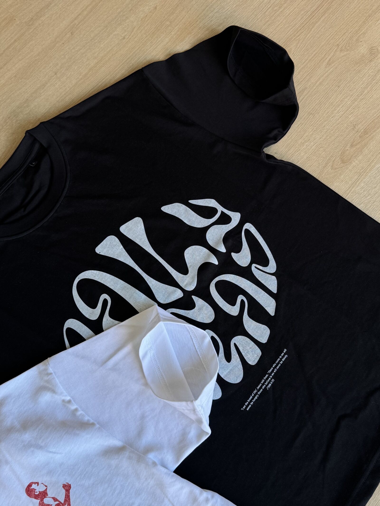 Flat lay of black and white t-shirts with typography graphics on wooden surface
